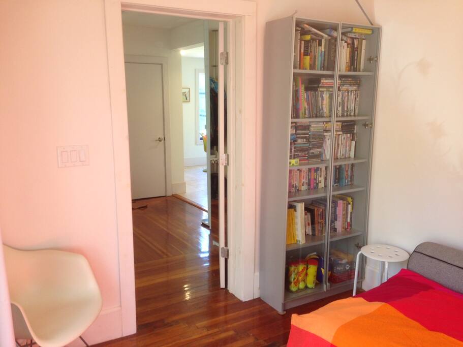 Bedroom door opening onto corridor, the mirror indicates where the closet is, which guests can use. Here is the DVD and book library.