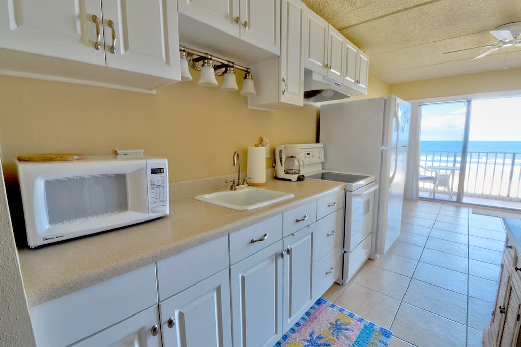 Newly remodeled kitchen features a full size refrigerator, 4-burner flat-top stove with oven, and plenty of counter space and storage. Fully stocked with pots, pans, dishes and utensils.