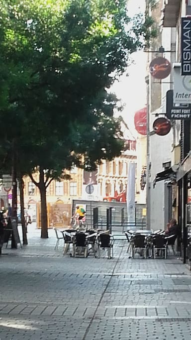 Les terrasses au pied de l'immeuble, et la Grand place au bout de la rue