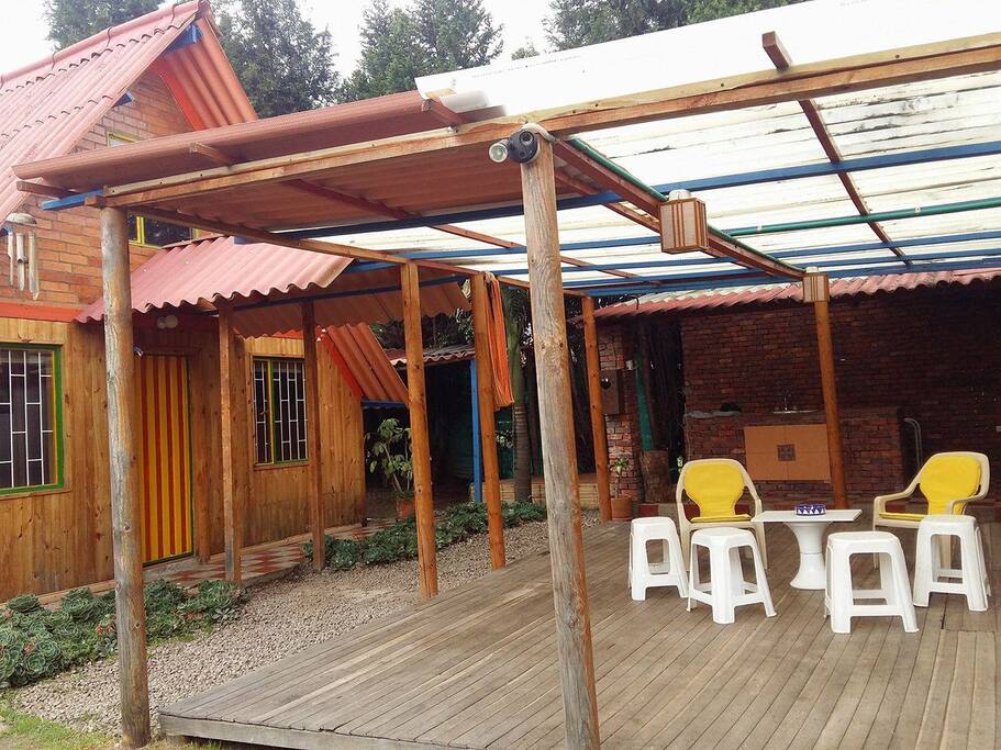 Cobertizo y fachada de la cabaña. Al fondo el BBQ