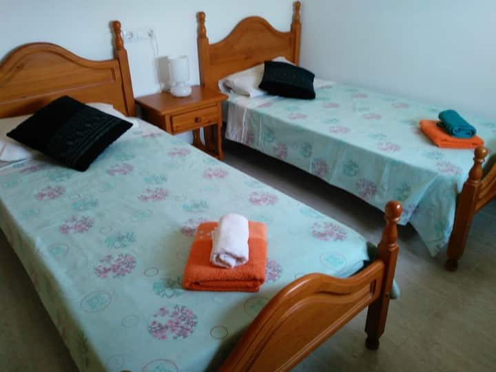 Bedroom Nr. 3 with two single beds, air conditioner, built-in wardrobe, ceiling fan and window.