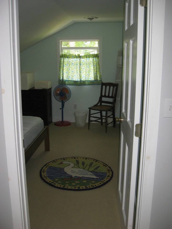 Cozy carpeted blue colored bedroom with double bed off wide, spacious hallway.