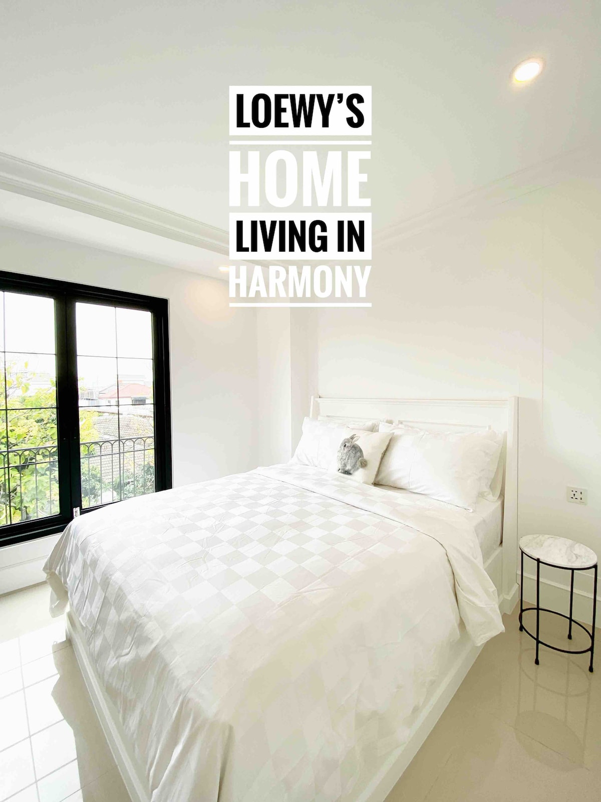 A bright sleeping area features a spacious bed dressed in premium linen, complemented by a bedside table. Large windows allow natural light to illuminate the room, enhancing the fresh and clean design.