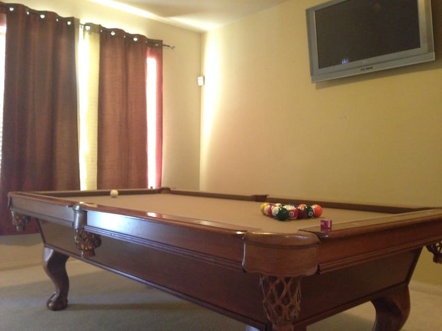 The pool table located in the entrance. It also comes with a mounted TV so you can stream from your phone to the TV while playing pool!