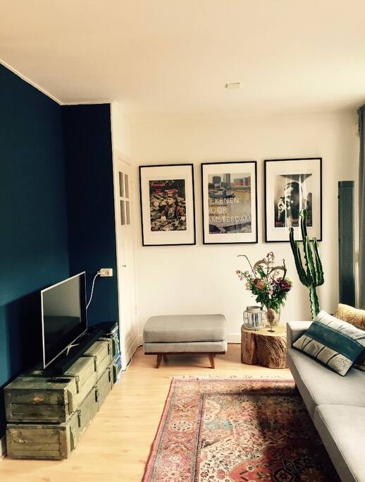Nice and light living room with a big screen, comfy couch and big windows.