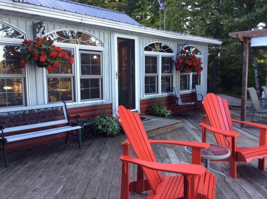 Large deck with 2 Muskoka chairs overlooks the lake.