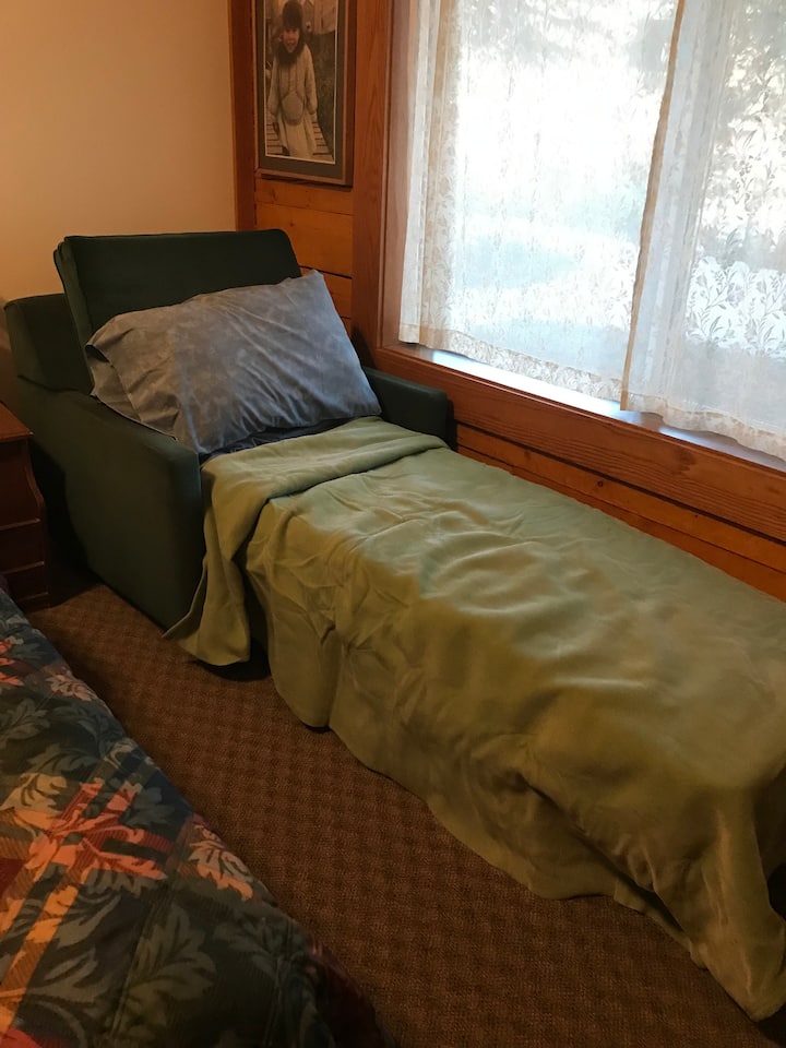 Chair in form of extra bed for one person.  Hide-a-bed with bedding
