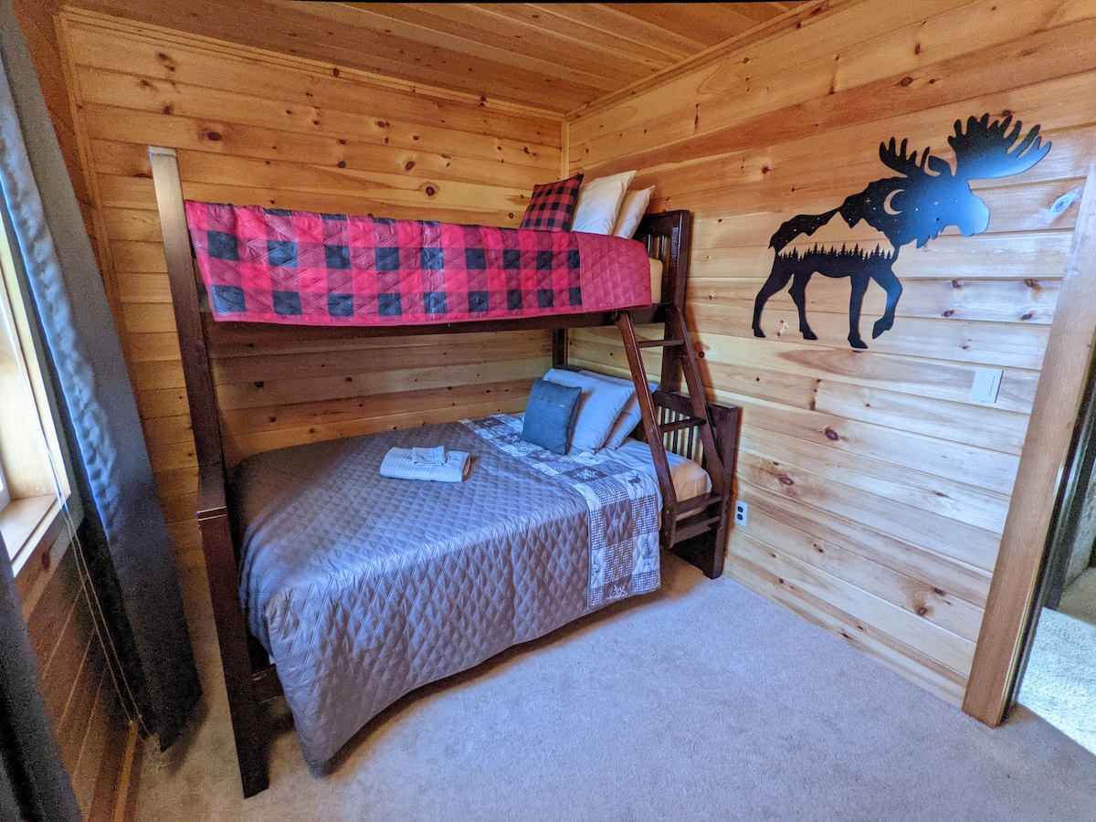 غرفة نوم بسرير بطابقين بسرير سفلي كامل الحجم وسرير علوي مزدوج الحجم. 