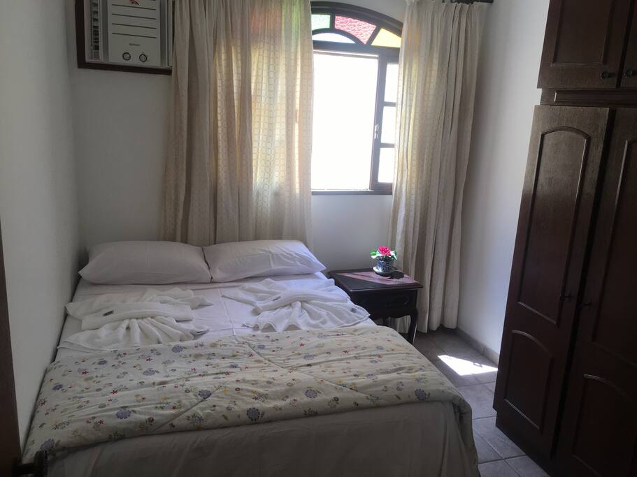 Quarto com cama de casal, armário, ar condicionado e ventilador de teto.