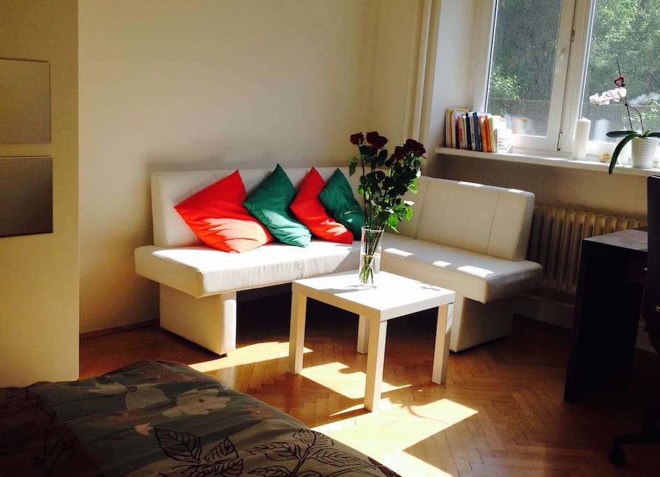 Private room with double bed, couch, writing table, chair, bedside table.