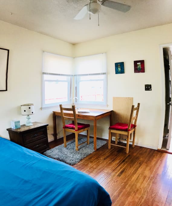 MAIN/FRONT ROOM. Comfortable futon bed down in bed position, and desk/dining table (as seen from the kitchen doorway). Notice the ceiling fan and double-hung windows.
Photo from Feb 2018
Photo by www.tc3Imagery.com