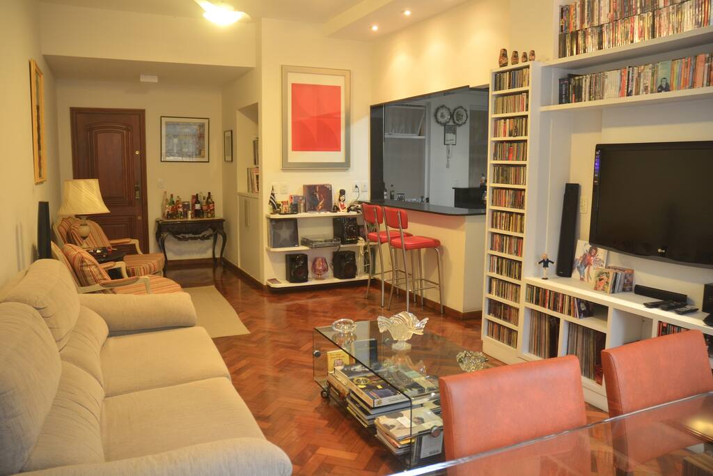 Sala com cozinha americana, destaque para balcão da cozinha americana com duas cadeiras.(Sofá-cama para 1 pessoa)