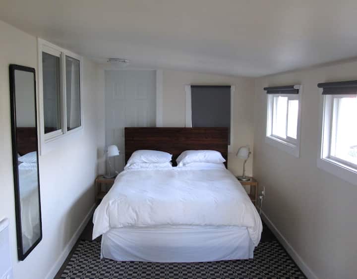 Tranquil third bedroom with plush queen sized bed and windows on every wall