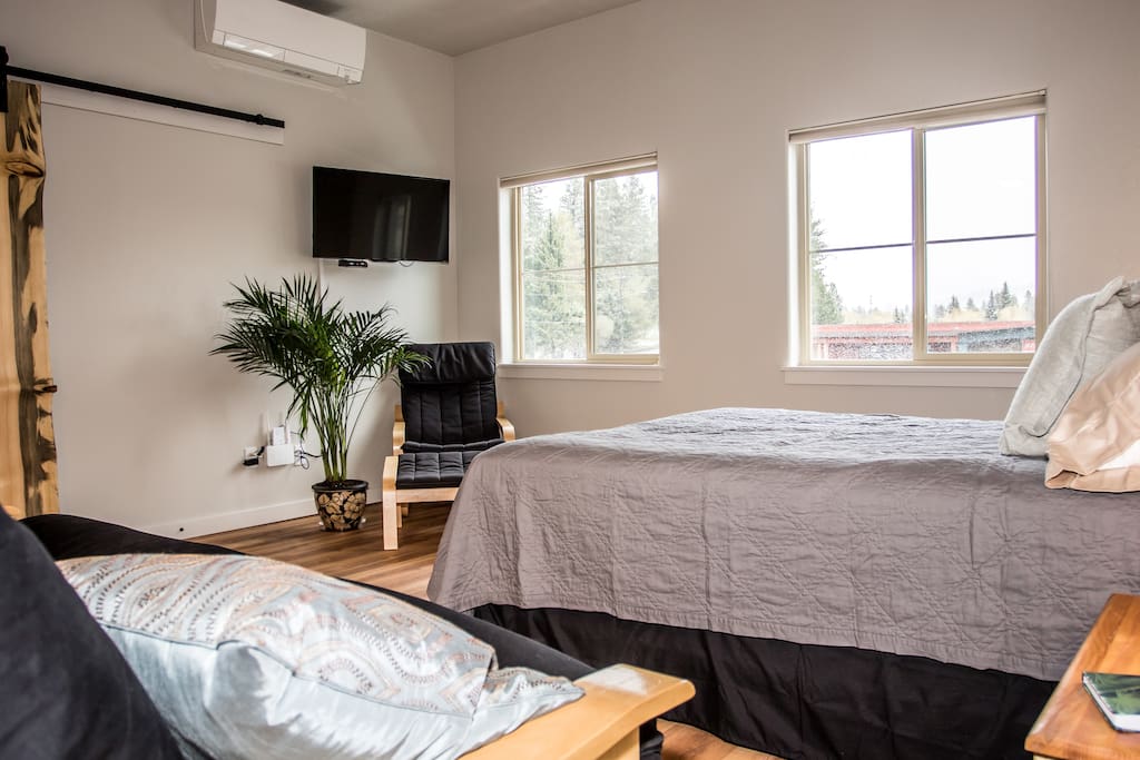 Queen size bed and futon with a smart TV and cable