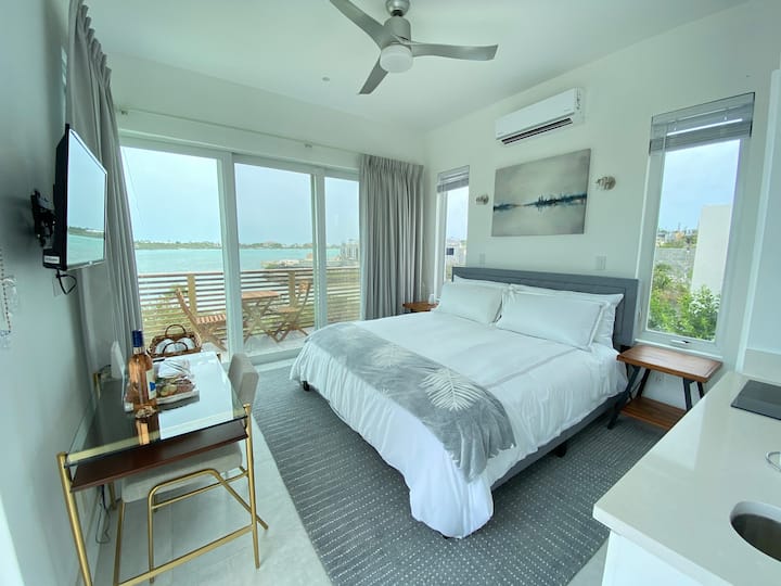Studio Bedroom in detached unit inclusive of kitchenette, en-suite bathroom, smart tv, AC, remote fan, office desk and chair, outdoor dining chair and table.