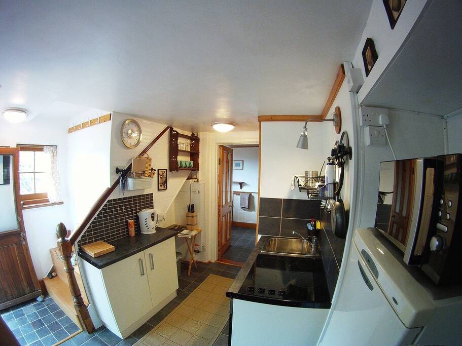 A galley kitchen with fridge freezer, oven, hob and microwave.