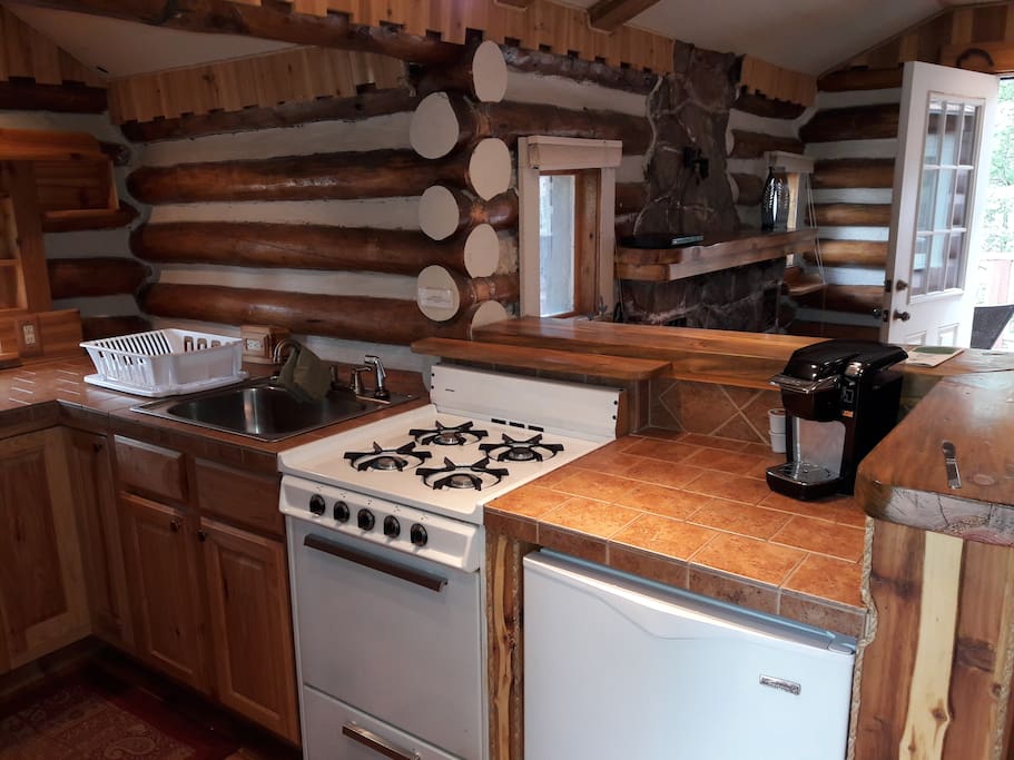 Kitchen with gas stove and small fridge.