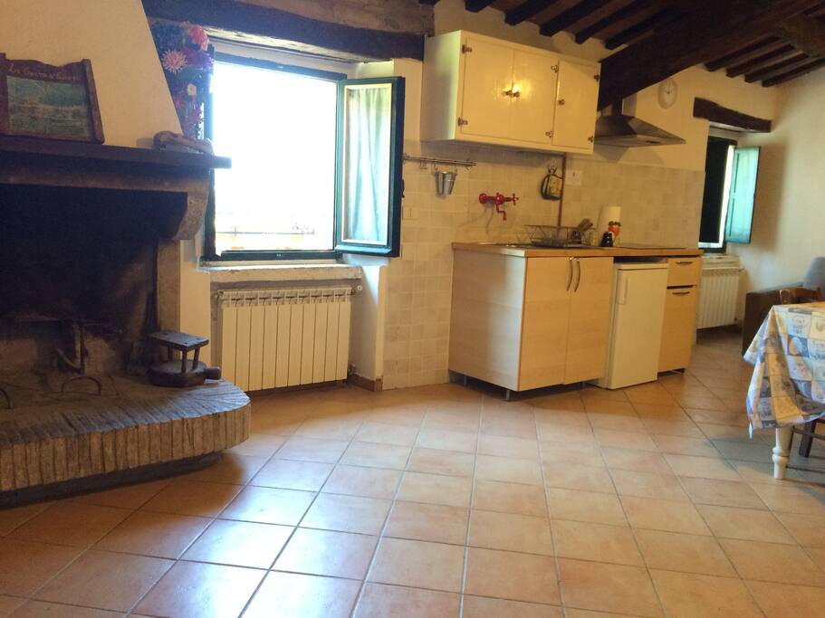 Zona giorno, con camino, angolo cucina, tavolo e divano letto