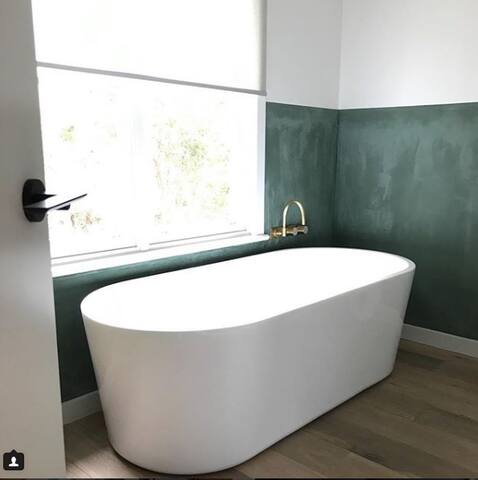 Ensuite bathroom features free standing tub and brass fixtures