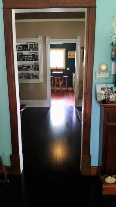 View of downstairs from living room through dining room and kitchen. Bedroom #1 is to immediate left, door to stairs up to second story left off dining room, hall to bathroom and door to back yard is a left just before the kitchen.