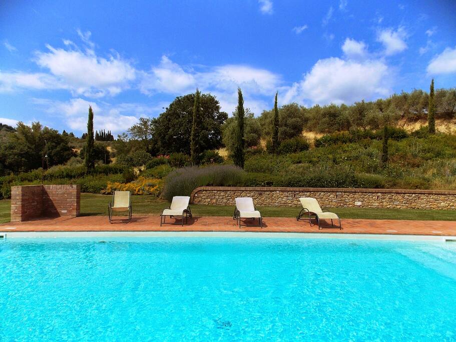 Swimming pool surrounded by sunbeds, beach chairs and umbrellas
