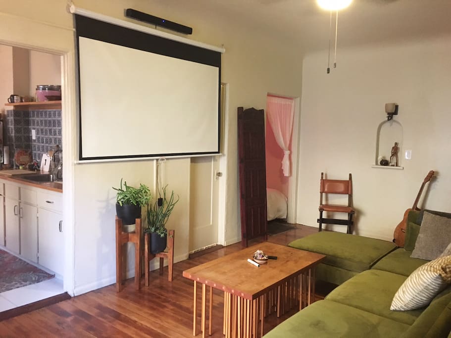 sun-filled relaxing living space with pull down projector screen and sound bar for movies!