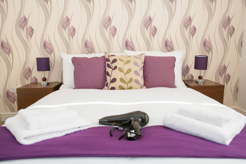 Beautifully decorated double bedroom with check of drawers, bedside cabinets, wardrobe and hairdryer.