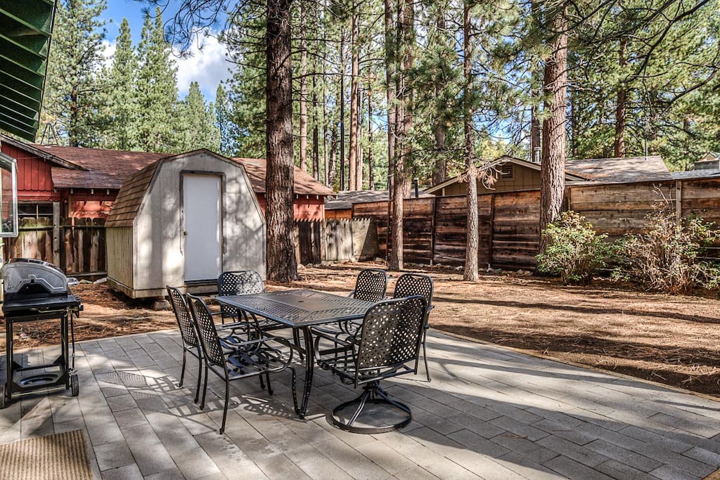 A secluded outdoor patio is shaded by pines.
