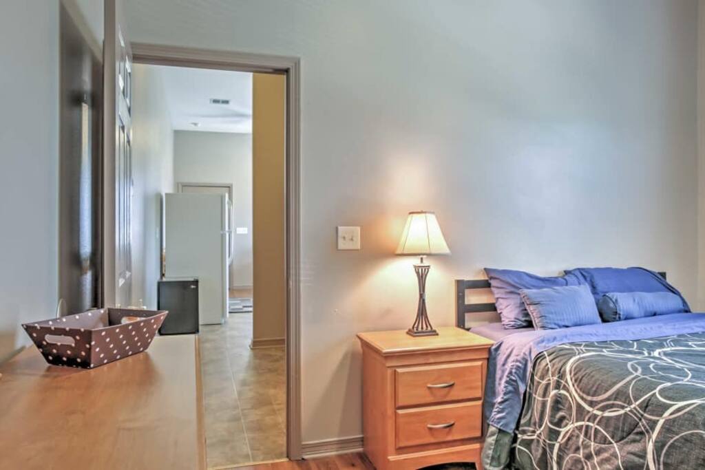 Bedroom and the doorway leading up to the living room, kitchen, and the front door entrance. The private bathroom is located to the right side