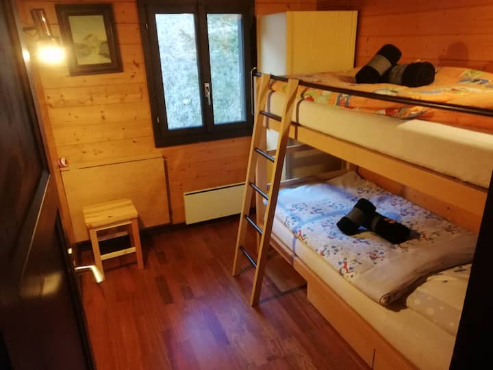 Dormitorio con litera, mesa plegable, taburete, armario y cajones de cama (ladera).
