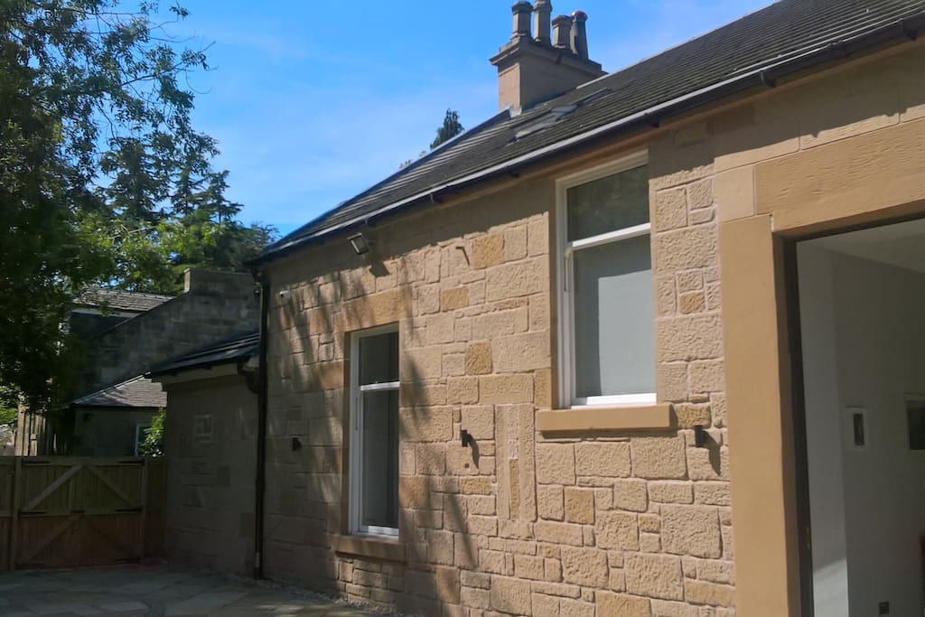 Rear view of house from patio showing kitchen diner and ground floor guest room window on left.