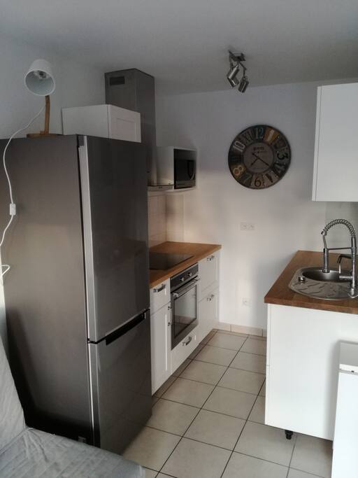 Cuisine équipée avec four, lave vaisselle, plaque induction, micro ondes/grill, hotte aspirante et combiné réfrigérateur/congélateur.