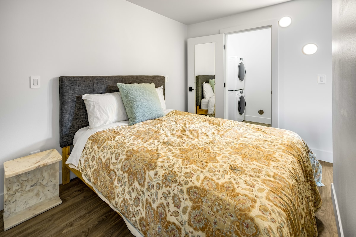 Queensize bed naast kast met wasmachine/droger