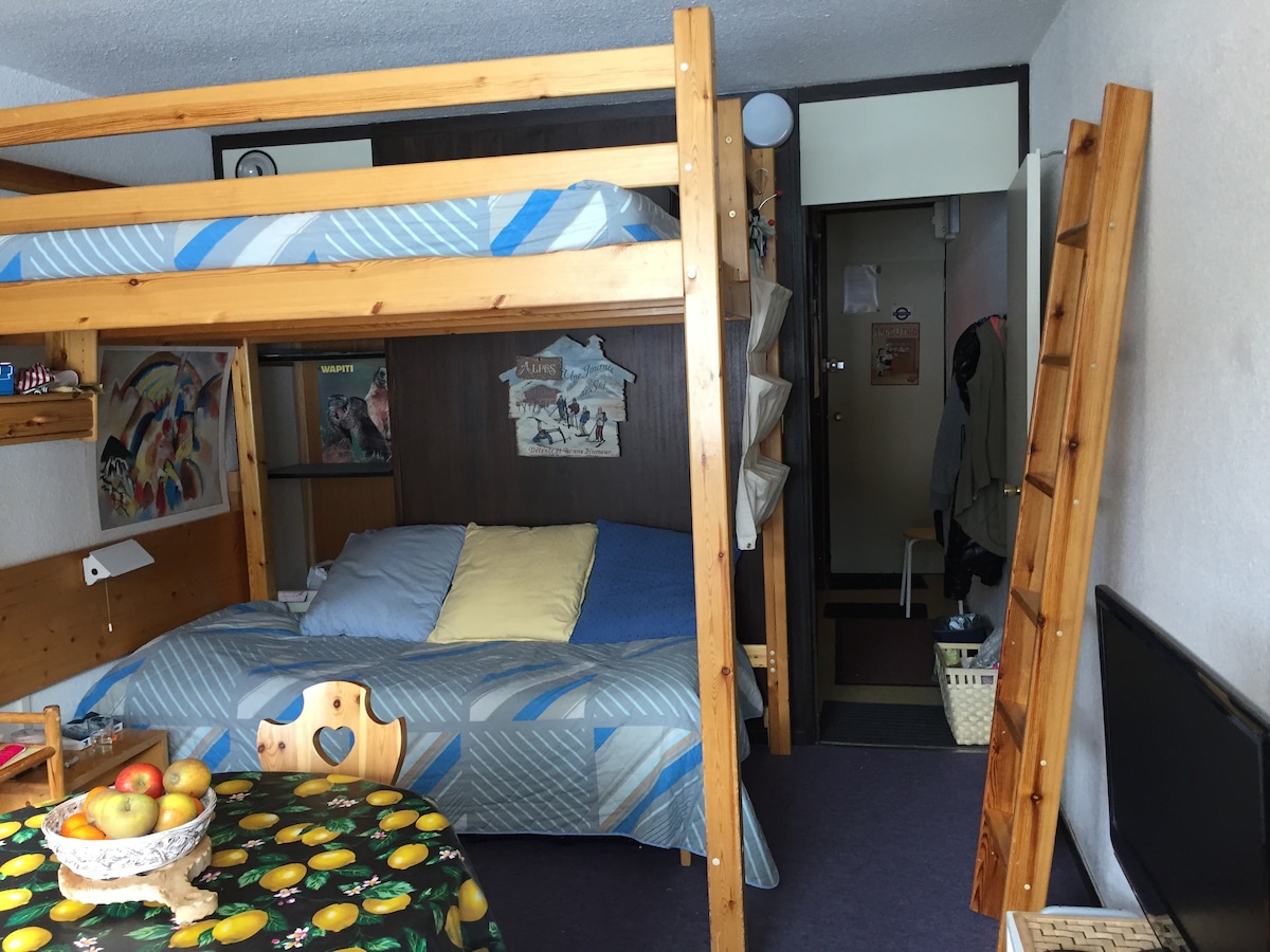 Cama nido y altillo; pasillo de acceso al baño a la izquierda , cocina y puerta de entrada al fondo .