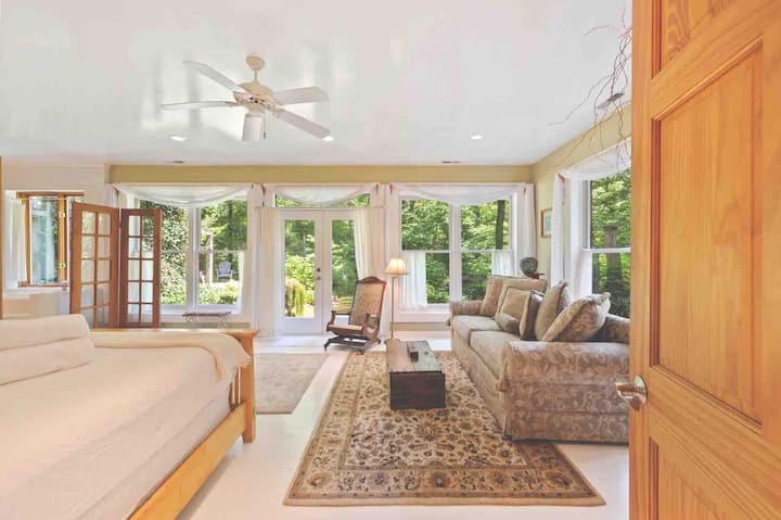 La superbe chambre principale avec vue sur le jardin est couverte de lumière naturelle. Il dispose d'un lit King Size avec des draps haut de gamme, d'un salon/canapé de lecture confortable et d'une salle de bain attenante avec douche et baignoire séparée face à la fenêtre. 