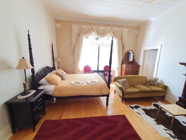 ที่พักที่สว่างไสวและน่าอยู่แห่งนี้มีแสงธรรมชาติสาดส่อง มีเตียงสี่เสาที่สวยงามเป็นจุดศูนย์กลาง และมีหน้าต่างแบบบานนอกที่มีเสน่ห์ประดับประดาด้วยรายละเอียดแสงสีที่ซับซ้อน เพิ่มความสง่างามและเอกลักษณ์ให้กับที่พัก