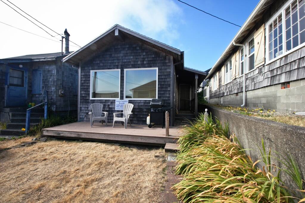 Street view of By the Sea with a small deck with gas BBQ and deck chairs