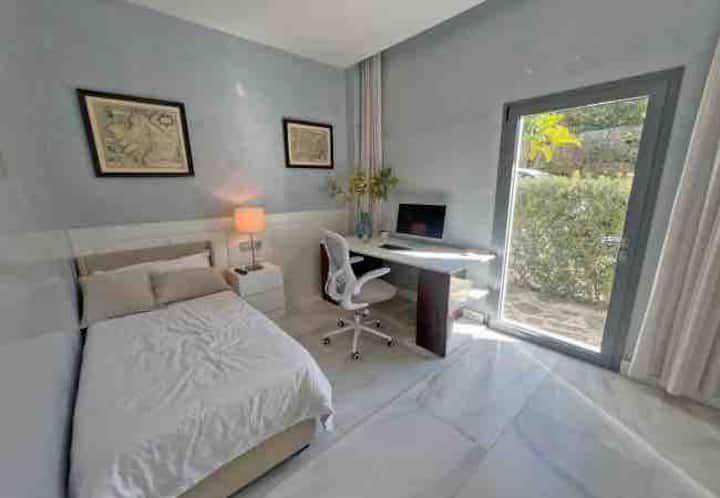 Dormitorio de invitados 5 con acceso directo al aire libre y baño privado. Se puede utilizar como dormitorio o sala de servicio. Hay un escritorio grande y una nueva televisión inteligente.