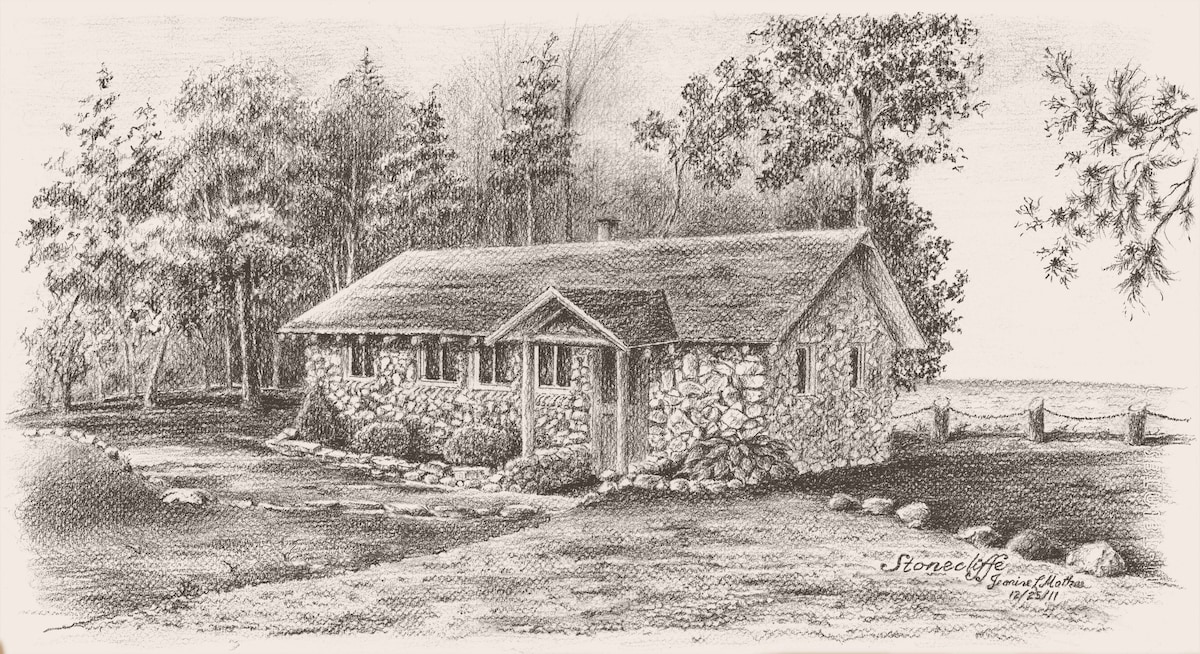 A hand-drawn sketch of Stonecliffe Cottage captures the rustic charm of the stone exterior. Surrounded by trees, the property features a simple roofline and several windows, with a glimpse of the lake visible in the background.