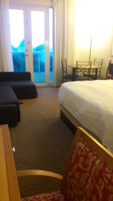 King-size bed with dining set and sofa bed in background.