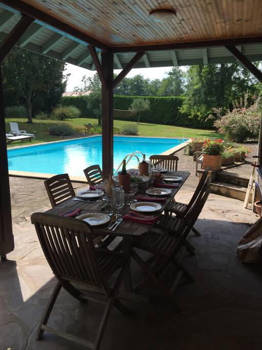 Al fresco dining area with built-in BBQ, overlooking pool.