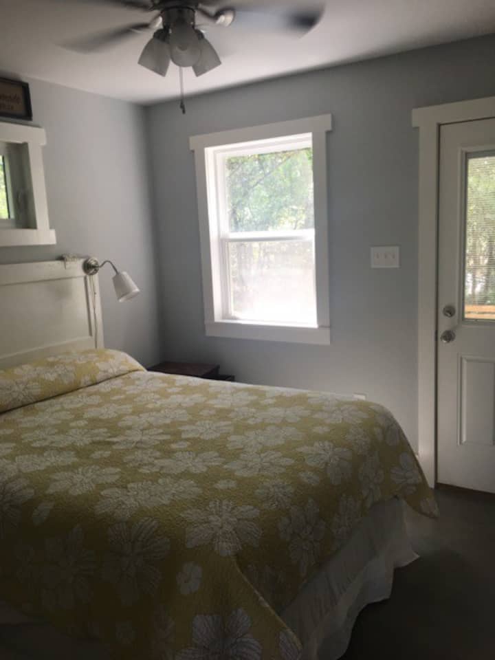 Master bedroom with queen bed and door to outdoor patio with porch swing. 