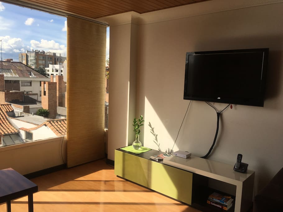 Flat screen TV in living room and wall to wall window with a gorgeous view of the exclusive Santa Barbara neighborhood.