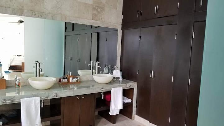 Baño con lavabo doble y ducha con pared de glss