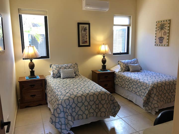 La habitación de invitados tiene ventanas operables, así como ventilador de techo y su propia calefacción o aire acondicionado mini-split.  La vista es a un patio cerrado y la habitación cuenta con armario incorporado, escritorio y estanterías con TV.