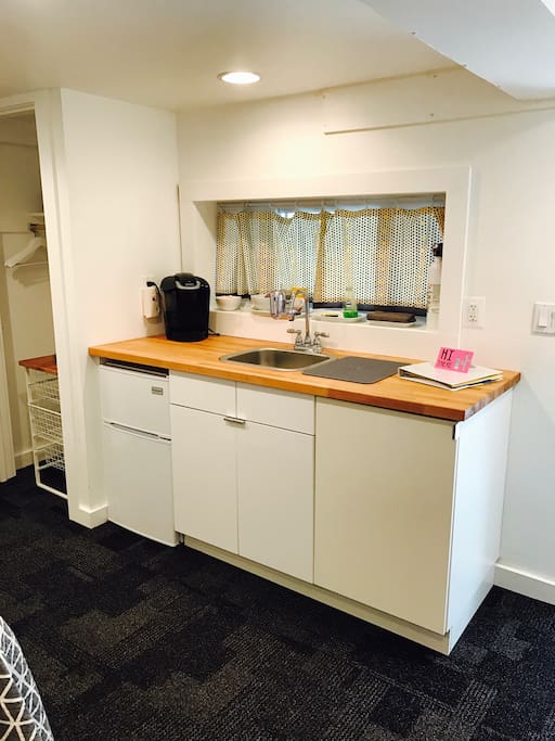 Kitchenette in room with Keurig coffee maker, mini fridge, microwave, glasses, plates, bowls, utensils