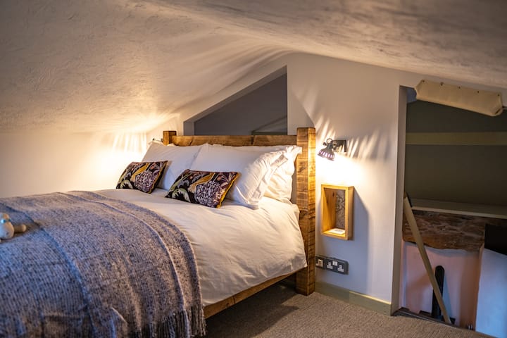 Мезанинот/платформата за спиење на горниот кат има брачен кревет со пердуви и чаршафи од египетски памук