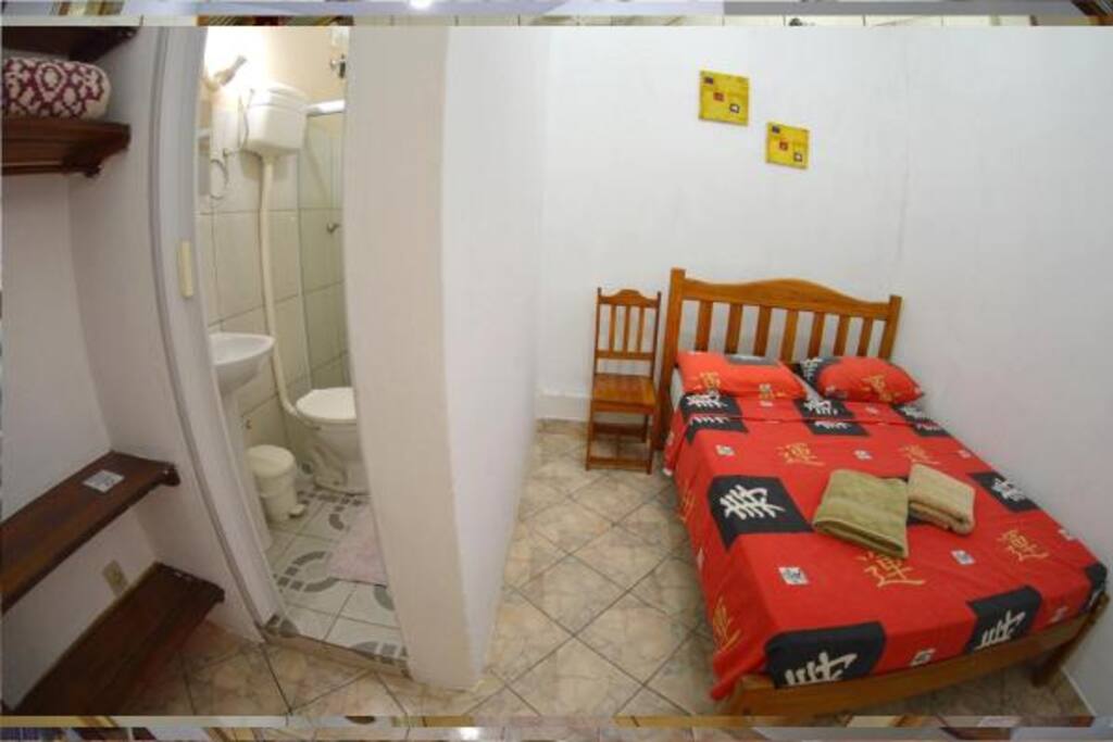 Quarto de Casal com ventilador de teto e banheiro privativo.