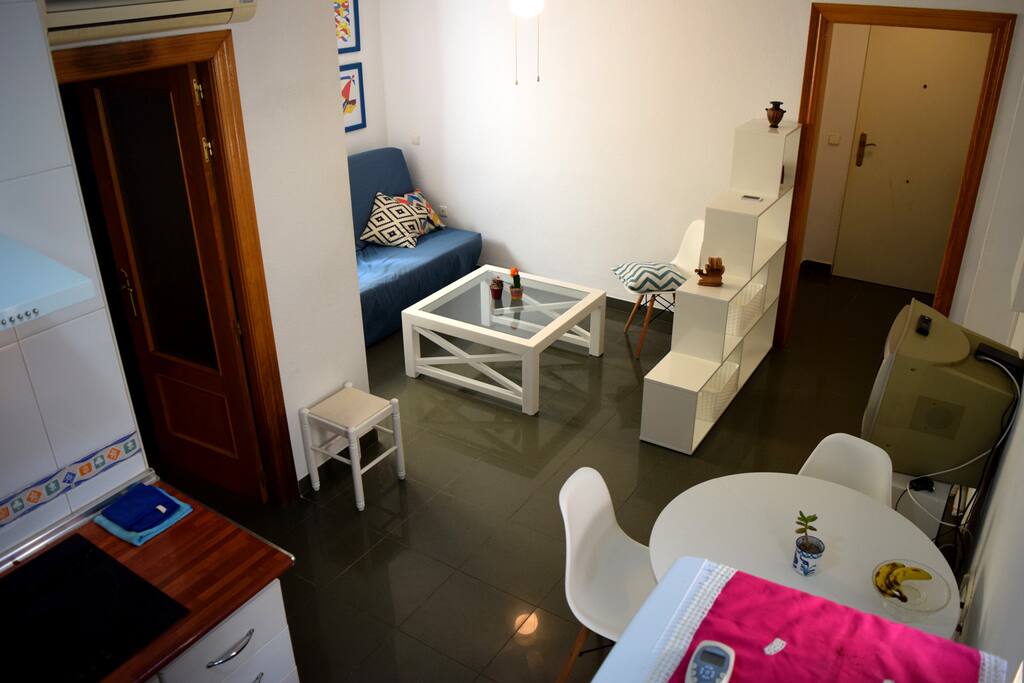 View from the kitchen of the living room with the entrance of the apartment and dining area. The entrance area has a clothes hanger for jackets, a shoe rack and some space for luggage / Vista desde la cocina del área de estar con el área comedor y la entrada del apartamento. El area de la entrada posee lugar para colgar chaquetas un mueble para los zapatos y dejar maletas.
