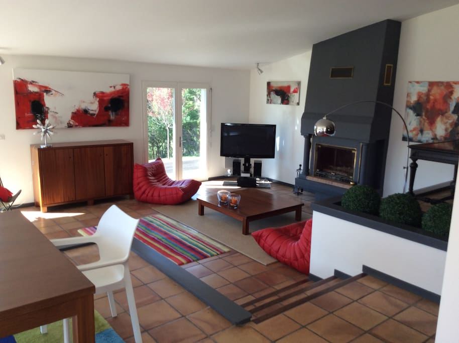 Large living room with fire place opened on the garden and sun light
